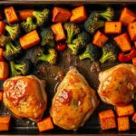 Golden honey garlic chicken thighs on a sheet pan with roasted broccoli, sweet potatoes, and bell peppers